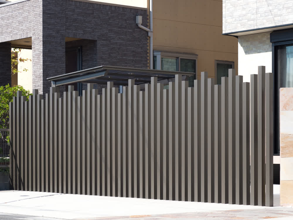 Staggered black post fence beside paved driveway